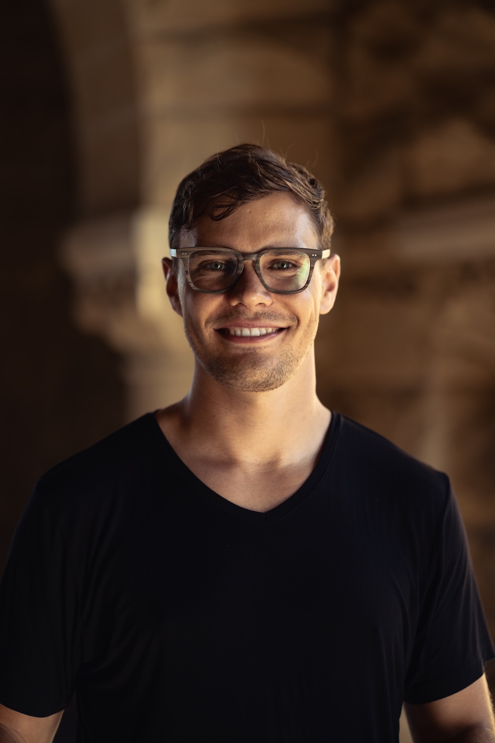 A photo of me smiling at the camera as the California sun sets over Stanford's sandstone quad.